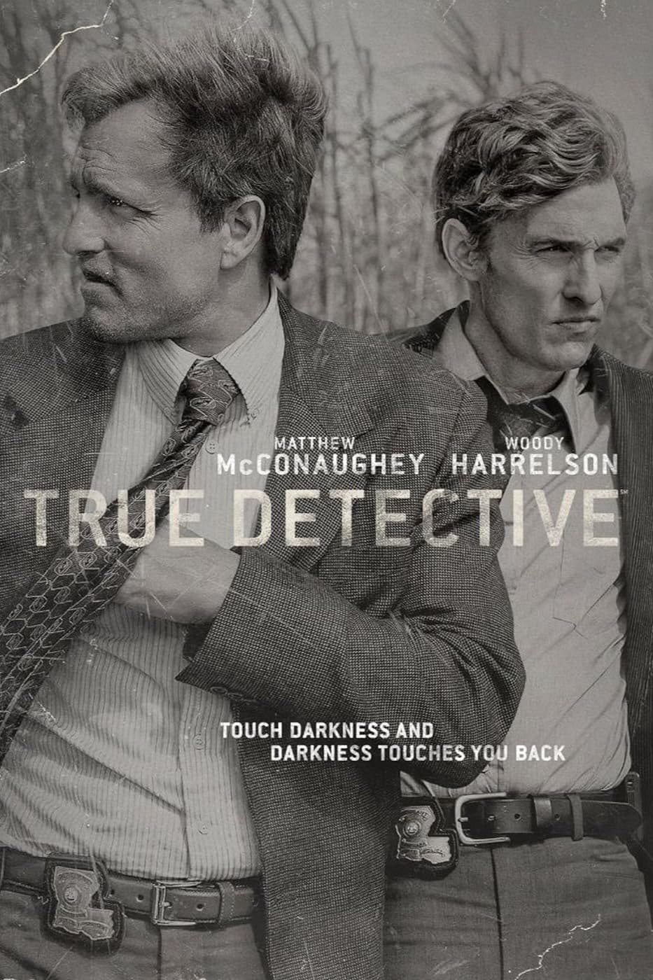 Two men in suits stand side by side outdoors, looking in different directions. Text reads: Matthew McConaughey, Woody Harrelson, True Detective. Immerse yourself in the mystery with IPTV BrasiL—touch darkness and darkness touches you back.