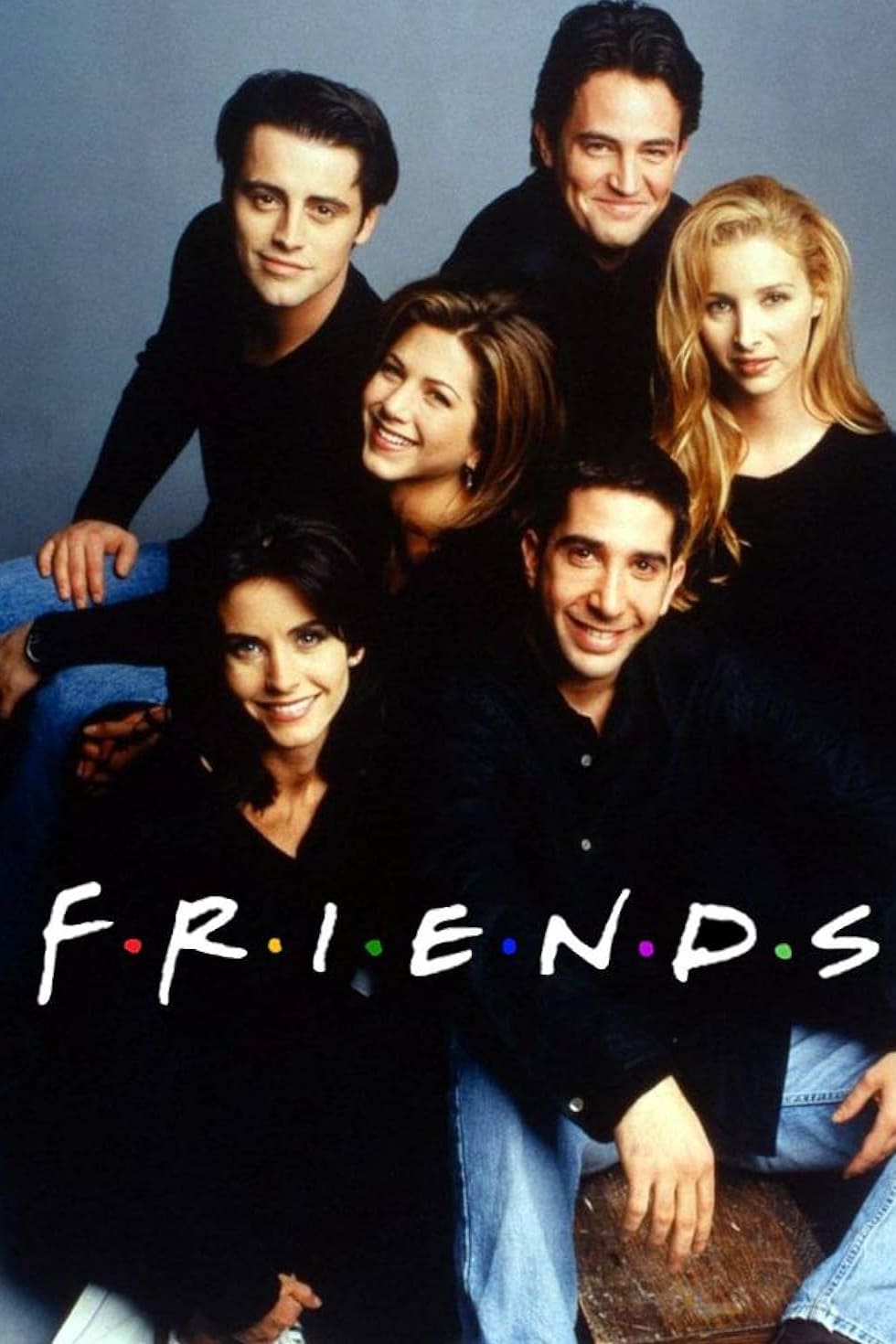 Six people sit closely together, smiling at the camera. The word FRIENDS is written across the bottom in white, with colorful dots between each letter. The background is gray, giving a cozy vibe reminiscent of your favorite sitcom—perfect for streaming on Brasil IPTV.