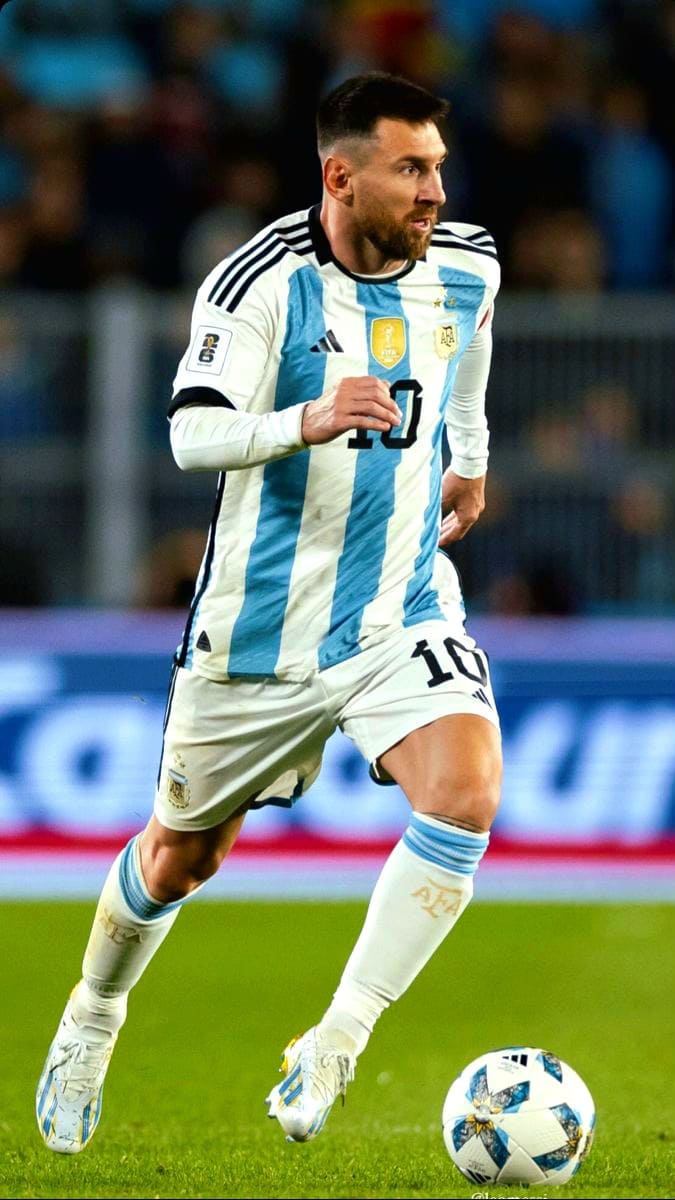 A soccer player in an Argentina jersey with the number 10 is running on the field while controlling a soccer ball during a match, as fans around the world tune in via Brasil IPTV to catch all the exciting action live.
